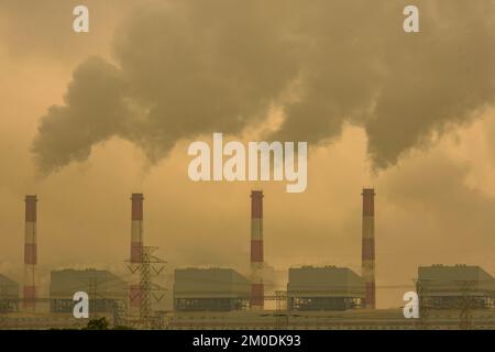 Colpo corto di centrale di carbone con vapore che fuoriesce dalla pila. Camino industriale di fumo della centrale a carbone al mattino. Foto Stock