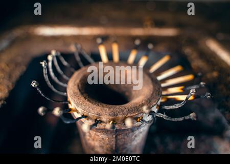 Fiammiferi di legno bruciati invece di fuoco nel bruciatore di una stufa a gas close-up. Basso tenore di vita, sopravvivenza in condizioni di povertà. Risparmio di gas naturale. S Foto Stock