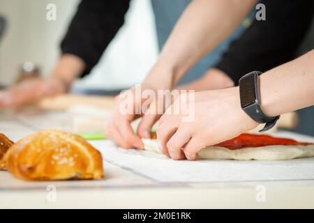 Primo piano sulle mani dei cuochi, cottura del panificio in una cucina luminosa da due chef, fuoco morbido selettivo Foto Stock