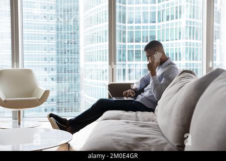 Serio occupato giovane uomo d'affari nero che parla su cellulare Foto Stock