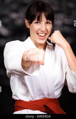 Impacchettare un potente pugno. Ritratto di una giovane donna che pratica il karate nel suo gi. Foto Stock