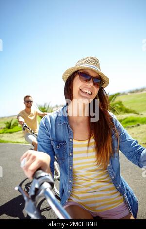 Giro in bicicletta beato. Una giovane coppia felice in bicicletta in un pomeriggio di sole. Foto Stock