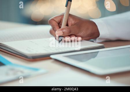 Primo piano sulle mani di un medico che scrive in un giornale. Pianificazione medico in un notebook. Medico afro-americano che utilizza un tablet digitale in ospedale Foto Stock