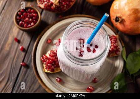 Frullato proteico vegano a base di melograno e banana su un rustico tavolo di legno. Cibo sano, stile di vita sano. Foodismo, dieta alimentare cruda. Foto Stock