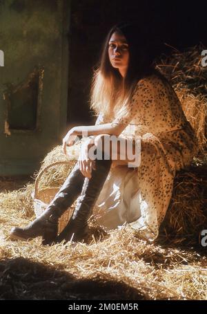 Giovane donna vestita in stile anni '70 e si sfoggia in un ambiente rustico Foto Stock