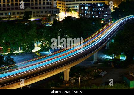 Treno di transito ferroviario leggero che attraversa la città di notte. Foto Stock