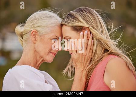 Una giovane donna caucasica che trascorre la giornata in spiaggia con la madre anziana. Donna bianca e sua madre sorridendo in spiaggia e abbracciandosi Foto Stock