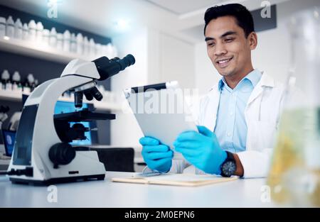 Scienza, tablet e microscopio con un uomo al lavoro in un laboratorio di ricerca o innovazione. Medico, medicina e assistenza sanitaria con un ingegnere maschile Foto Stock