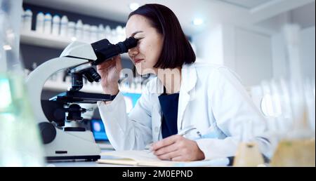 Donna scienziata, microscopio e laboratorio con scrittura, libro e sviluppo di vaccino, cura o medicina. Esperto medico asiatico, strumenti scientifici e. Foto Stock