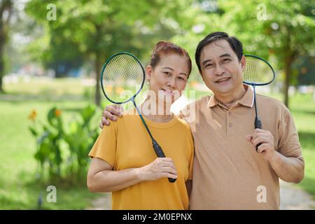 Ritratto di felice coppia anziana con racchette di badminton in piedi nel parco Foto Stock