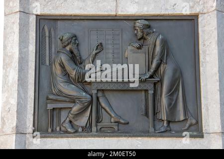 Rappresentazione della creazione della bibbia di Gutenberg sulla statua di Johannes Gutenberg, Magonza, Germania. Foto Stock