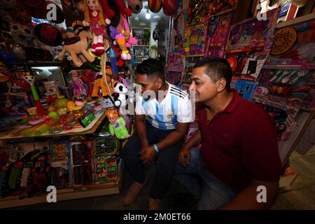 Un negoziante guarda la partita Brasile / Corea del Sud sul suo telefono cellulare in un negozio di giocattoli nel Souq, Doha, Qatar. Data immagine: Lunedì 5 dicembre 2022. Foto Stock