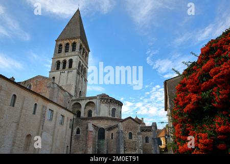 Chiesa dell'Abbazia di Saint Philibert a Tournus, Borgogna, Francia, con la sua facciata esterna romana e fiori colorati in primo piano Foto Stock