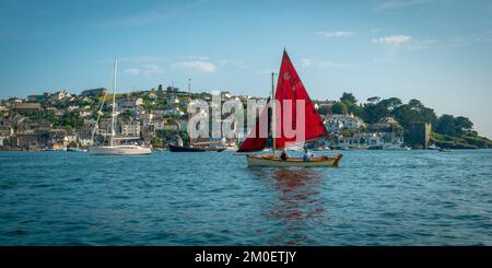 22nd luglio 2021 - Fowey, Regno Unito: La vista da una gita in barca intorno al porto di Fowey, Cornovaglia e la sorprendente vela rossa su una piccola barca di passaggio. Guardando verso Polruan. Foto Stock