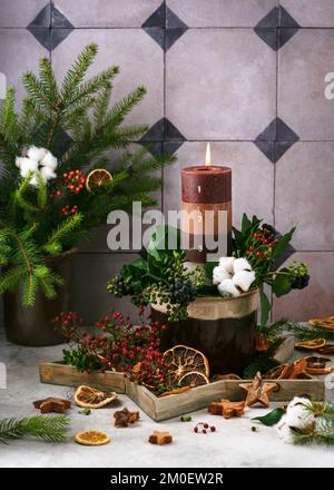 Bruciare gli strati di Natale candela con 4 numeri di Avvento decorato con materiale naturale, fette di arancio secco, abete, edera e rami di bacche rosa Foto Stock