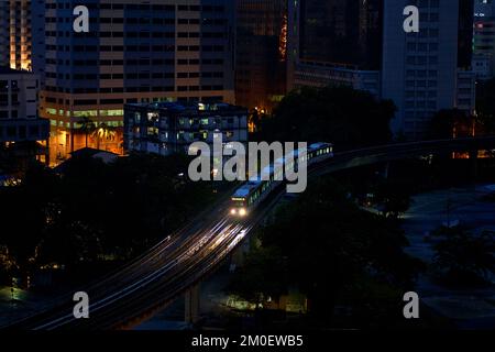 Treno di transito ferroviario leggero che attraversa la città di notte. Foto Stock