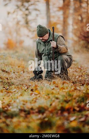 Cacciatore o ranger con pistola o fucile con un cane nella foresta caccia di alcuni veleno, periodo di caccia, stagione autunnale, caccia e concetto di persone Foto Stock