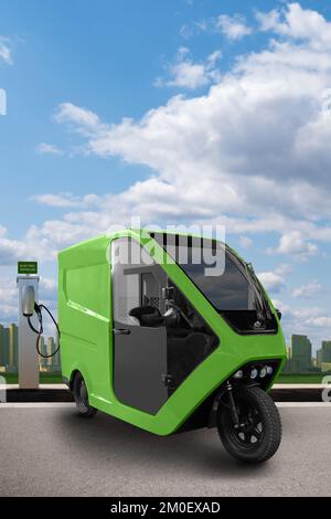 Concetto di scooter triciclo elettrico a consegna verde con stazione di ricarica su sfondo urbano Foto Stock