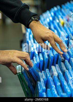 Mani nella ricerca e nella scelta di film e dvd su uno scaffale nel negozio di un collezionista di film e nella vendita di dischi per il merchandising Foto Stock