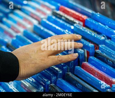 Mani nella ricerca e nella scelta di film e dvd su uno scaffale nel negozio di un collezionista di film e nella vendita di dischi per il merchandising Foto Stock