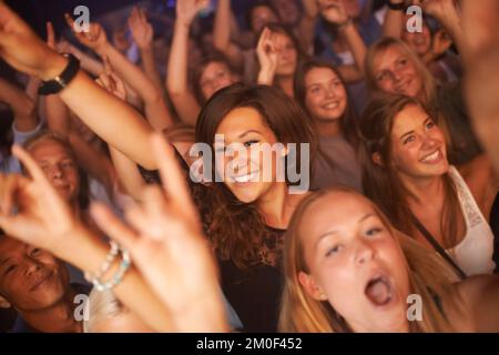 Tifosi, pubblico e persone al concerto, festival di musica e band performance con felice energia, mentre ballare in festa per i nuovi anni. Donne folla Foto Stock