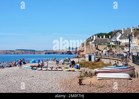 I turisti si rilassano sulla spiaggia e sul lungomare con vista sul mare e le scogliere, Sidmouth, Devon, UK, Europa. Foto Stock