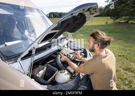 Uomo che fissa un furgone all'aperto Foto Stock