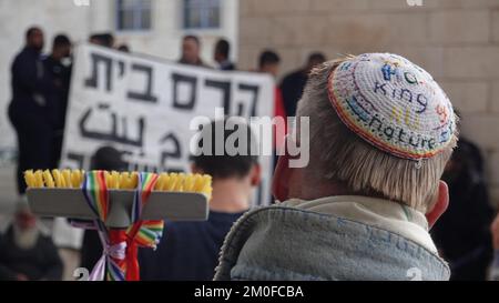 GERUSALEMME, ISRAELE - DICEMBRE 6: Un onlooker israeliano che indossa una cuffia yarmulke guarda i palestinesi partecipare a una manifestazione al di fuori del comune di Gerusalemme, detenuta dai palestinesi residenti nella zona di Wadi Qaddum del quartiere di Silwan, contro il piano del comune di demolire un edificio di 12 unità abitative nel loro quartiere il 6 dicembre 2022 a Gerusalemme, Israele. Le demolizioni delle case nei quartieri palestinesi sono presumibilmente eseguite perché le case possono essere state costruite senza permessi. Credit: Eddie Gerald/Alamy Live News Foto Stock