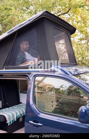 uomo sdraiato nella tenda pop-up del suo camper Foto Stock