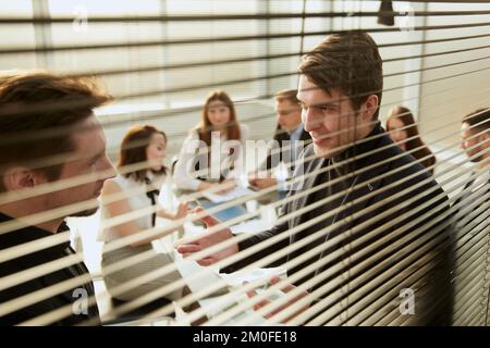 attraverso i ciechi. colleghi d'affari che discutono di questioni di lavoro . Foto Stock