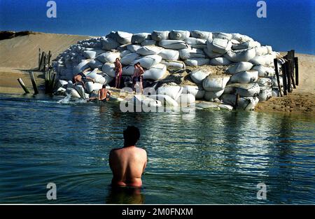 La 26enne Prestige affondò sul fondo del mare al largo della Spagna dopo essere entrata in due sette mesi fa. Ancora oggi la zona è colpita dal disastro. Anche se il governo dice che il 98% delle spiagge sono pulite, si possono vedere e odorare i resti di petrolio di ogni cosa nella zona. Immagini: Capo Corrubedo è sigillato con sacchi di sabbia e i ragazzi li usano come tavole da immersione. Foto Stock