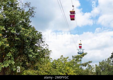 La funivia rossa galleggia su un'imbragatura per il trasporto da parte di visitatori e viaggiatori che sono venuti in questo parco a tema e cercano l'ambiente sopra l'alto Foto Stock