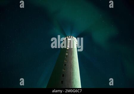 Un'inquadratura ad angolo basso di un faro a Gardur, Islanda, sotto l'aurora boreale nel cielo notturno Foto Stock