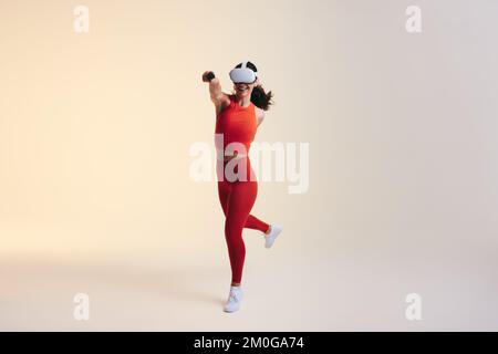Felice giovane donna che si diverte mentre si gioca un gioco di fitness realtà virtuale. Giovane donna attiva che lavora con la tecnologia 3D. Donna allegra che indossa v Foto Stock