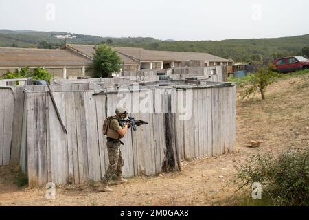 Il giocatore Airsoft in posizione tattica offensiva avanza per prendere posizione. Lo sport che mette alla prova le tue abilità tattiche Foto Stock