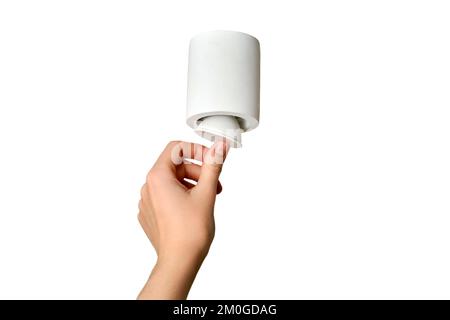 Una donna cambia una lampadina a risparmio energetico per soffitto con una lampada a LED in un salotto di casa, isolata su uno sfondo bianco. Lavori in quota autonomamente, fai da te Foto Stock
