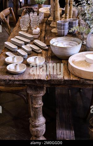 Fila di tavoli di casale in legno intemperiato e afflitto con piatti in porcellana Foto Stock