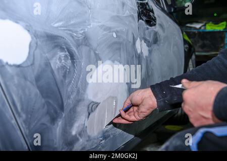 Lavoratori di lamiera, modellando con lo stucco, il corpo di un'automobile Foto Stock