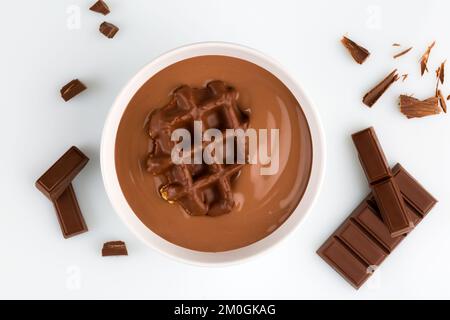 Budino al cioccolato in una ciotola con vista dall'alto della barra di cioccolato isolata sul bianco Foto Stock