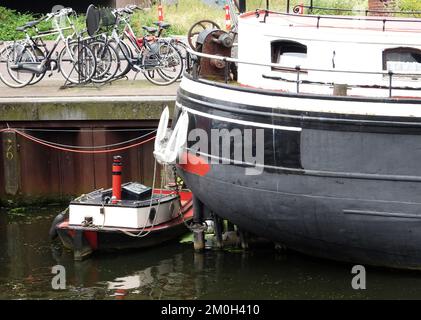 Amersfoort, Paesi Bassi - 23 2016 luglio Una piccola barca ormeggiata al molo di fronte ad una grande nave. C'è un portabiciclette pieno di biciclette sul molo Foto Stock