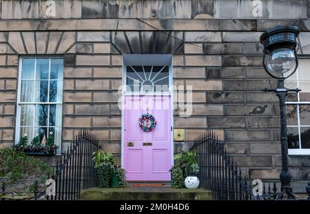 Edimburgo New Town, Scozia, Regno Unito, 6th dicembre 2022. Ghirlande e decorazioni della porta di Natale: I residenti nelle case georgiane della città nuova sono ben noti per le loro splendide decorazioni. Nella foto: La controversa porta rosa in Drummond Place con una corona di Natale. Credit: Sally Anderson/Alamy Live News Foto Stock