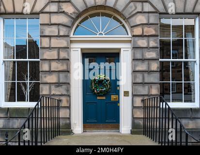 Edimburgo New Town, Scozia, Regno Unito, 6th dicembre 2022. Ghirlande e decorazioni della porta di Natale: I residenti nelle case georgiane della città nuova sono ben noti per le loro splendide decorazioni. Una corona di Natale su una porta d'ingresso. Credit: Sally Anderson/Alamy Live News Foto Stock