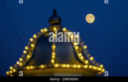 Brighton UK 6th dicembre 2022 - la Luna fredda di dicembre sorge sul lungomare di Brighton come un periodo freddo di tempo è previsto per colpire la Gran Bretagna nei prossimi giorni . : Credit Simon Dack / Alamy Live News Foto Stock