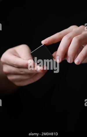 Le mani di Mans che tengono una piccola scatola nera quadrata con uno spazio vuoto della copia per il testo ed il disegno isolato su fondo scuro. Scheda, vuota, modello, mockup, Foto Stock