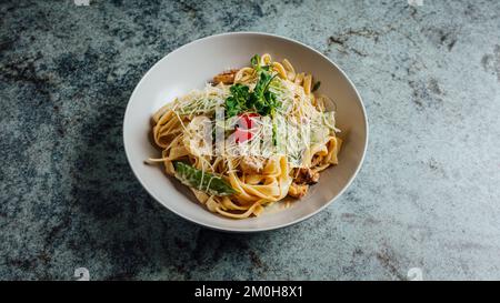 Un primo piano di deliziosa pasta condita con basilico, formaggio e pomodoro Foto Stock