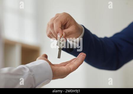 Primo piano irriconoscibile agente immobiliare maschile consegnando la chiave al nuovo proprietario di appartamento. Foto Stock