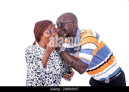 l'uomo adulto sussurra un segreto interessante nell'orecchio di una donna. donna che ricopre la bocca con la mano. Foto Stock