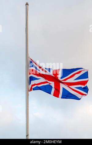 Bandiera di Union Jack che vola a metà albero contro un cielo blu chiaro e bianco opaco in occasione della morte della regina Elisabetta II Foto Stock