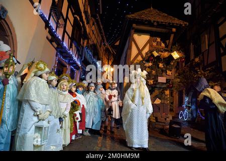 Francia, Alto Reno, Eguisheim, il Christkindel con la sua corona di candele e gli angeli accompagnano i molti bambini che tengono le loro lanterne per la Processione delle luci nei vicoli della città, rende omaggio a Santa Lucia, uno dei caratteri tradizionali del Natale alsaziano Foto Stock