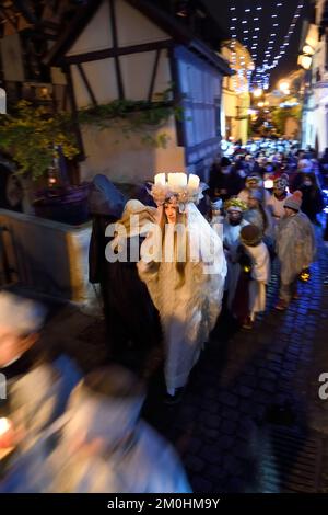 Francia, Alto Reno, Eguisheim, il Christkindel con la sua corona di candele e gli angeli accompagnano i molti bambini che tengono le loro lanterne per la Processione delle luci nei vicoli della città, rende omaggio a Santa Lucia, uno dei caratteri tradizionali del Natale alsaziano Foto Stock